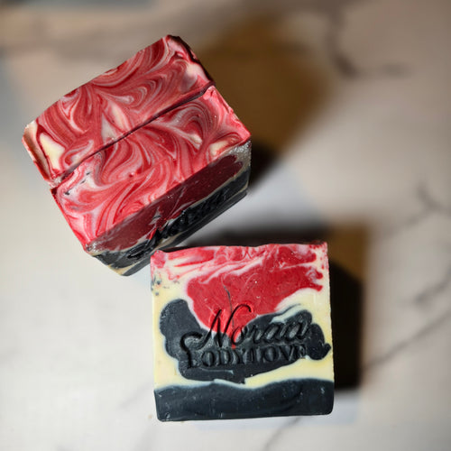 Marbled red, black, and white Noraa Body Love soap bars with a brand name on a neutral background